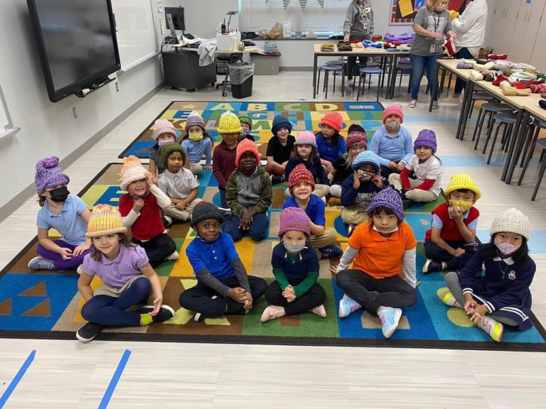 DMKA kindergartners wearing winter hats made by the RLC Knit & Crochet group, photo 1 of 6