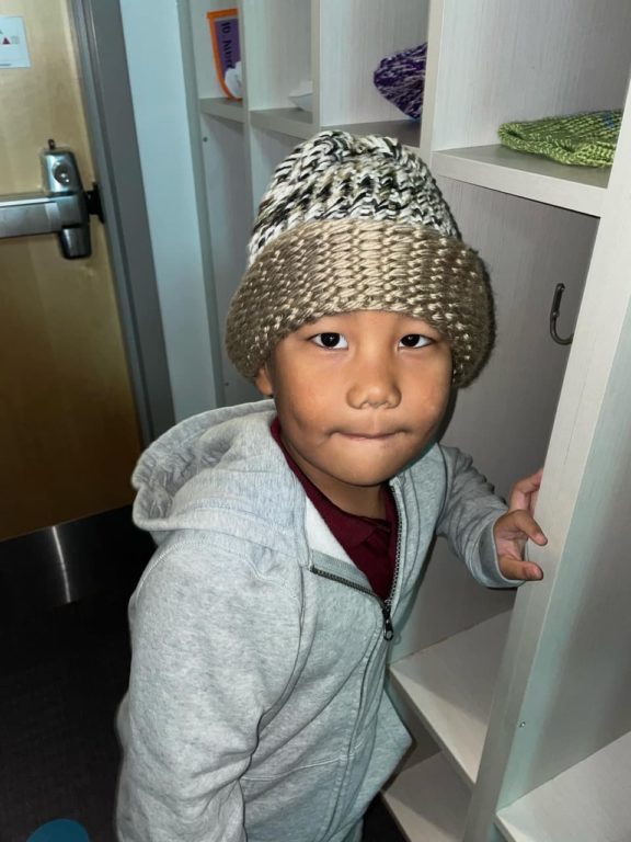 DMKA kindergartner wearing winter hat made by the RLC Knit & Crochet group, photo 2 of 6