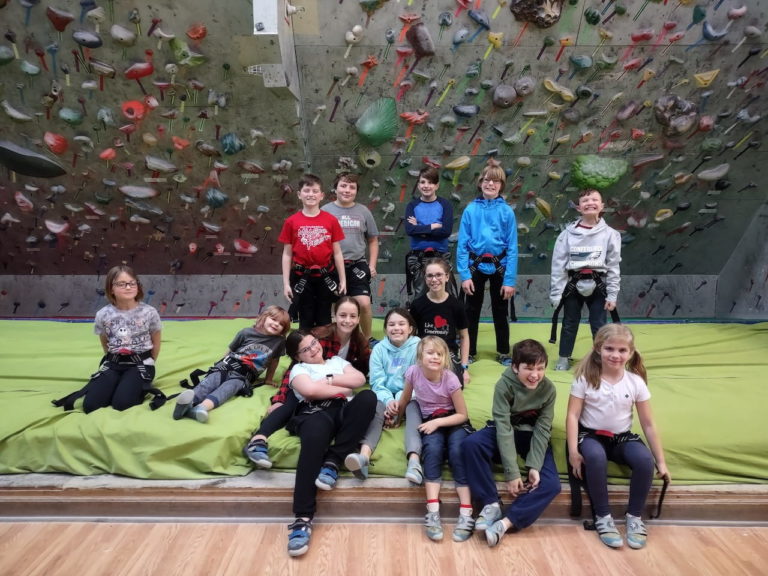 RLC Kids Club group of kids gathered in front of rock climbing wall